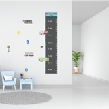A child's height chart decal styled on a white wall in a bright, modern children's room. The vertical black and white road-style height chart shows measurements from 0.