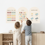 Two children standing in front of educational posters on a wall.