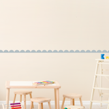 Children's play area with table, stools, and toys against a scallop pattern wallpaper border wall.