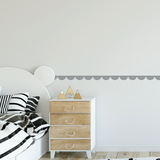 Wooden dresser with decorative items next to a bed with Scallop Pattern Wallpaper border on wall