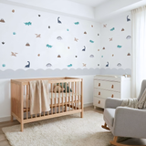 Nursery room with wooden crib, white dresser, and dinosaur wall decals.