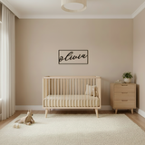 A rectangular nursery signage with a wooden frame and a name plaque in the center.